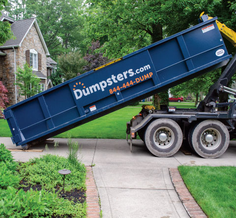 a roll off dumpster being delivered in a homeowner's driveway