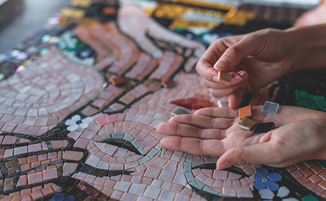 Hands holding multi-colored old tile pieces to be reused in art or home project.