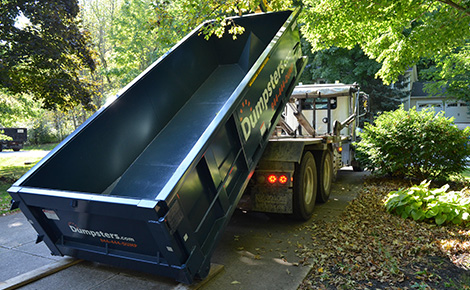 A roll-off dumpster being unloaded on a customer's driveway.