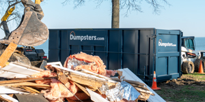 dumpsters.com roll off dumpster with construction debris piled nearby