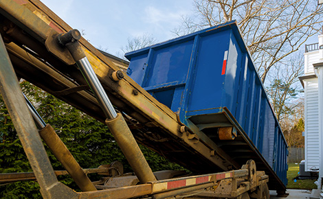 Roll-off dumpster being unloaded from truck. 