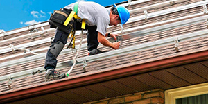 man in blue hard hat working on roof