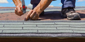Roofer's Hands Nailing Down Shingles