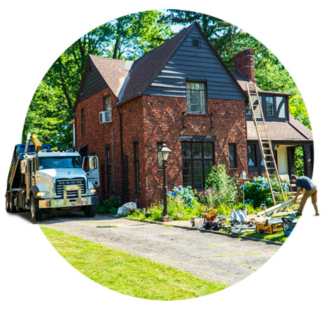 circle image of a roll off dumpster truck parked next to a red brick house
