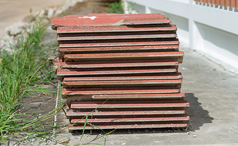 A pile of old tiles sitting on cement curb for recycle, reuse or disposal.