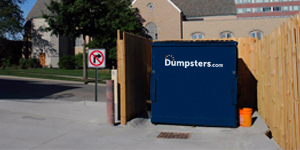 commercial dumpster in a wood enclosure near a public street