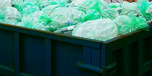 plastic bags filled with trash inside dumpster