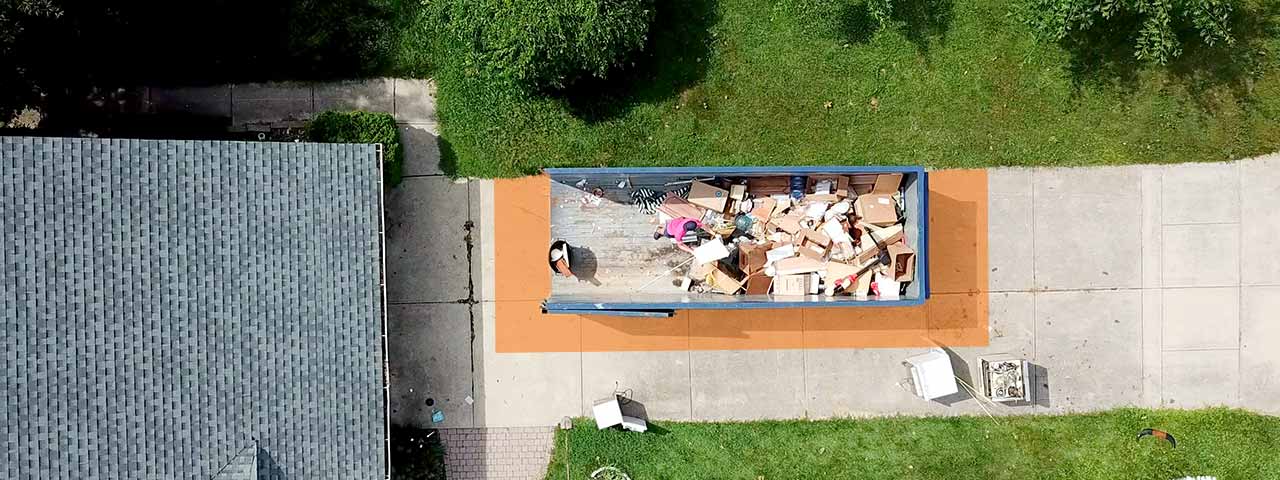 Overhead view of a filled roll off dumpster in a driveway.