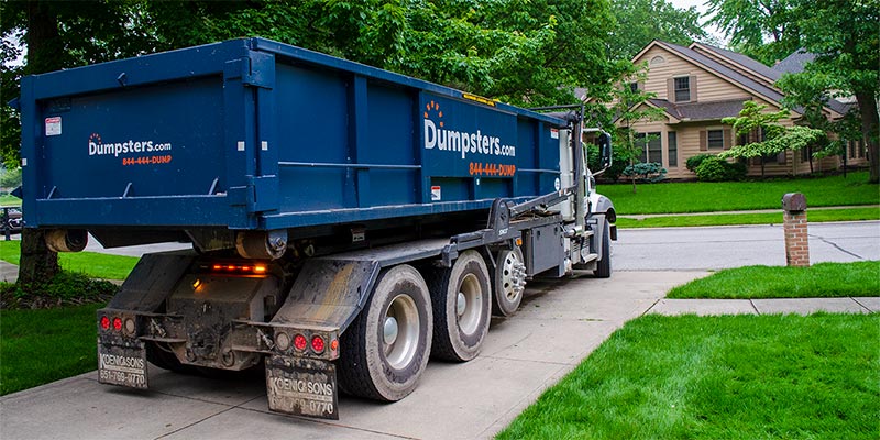 Alt Text: Roll Off Dumpster on Truck in Driveway.