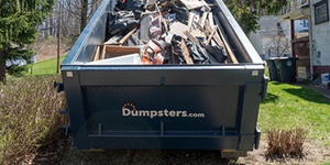 A Dumpsters.com roll off dumpster filled with debris.