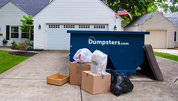 trash in front of roll off dumpster in a driveway
