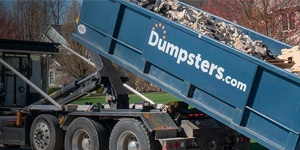 A Blue Dumspters.com Roll Off Dumpster Filled With Heavy Debris.