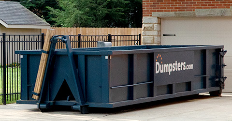 Roll Off Dumpster Next to a Black Gate in a Driveway.