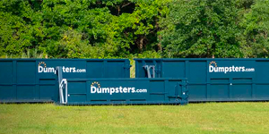 Three dumpsters.com containers in a green field. 