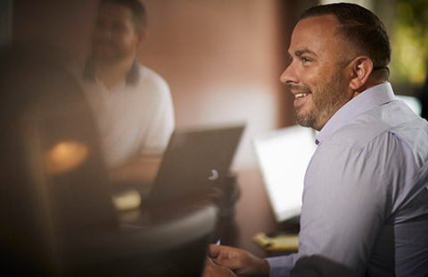 Dumpsters.com team member smiling in a meeting with other employees