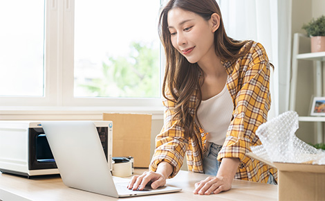 Woman posting her used microwave online on her laptop.