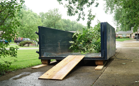 A roll off dumpster with yard waste debris inside.